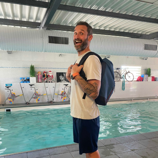 homme portant un sac à dos devant une piscine